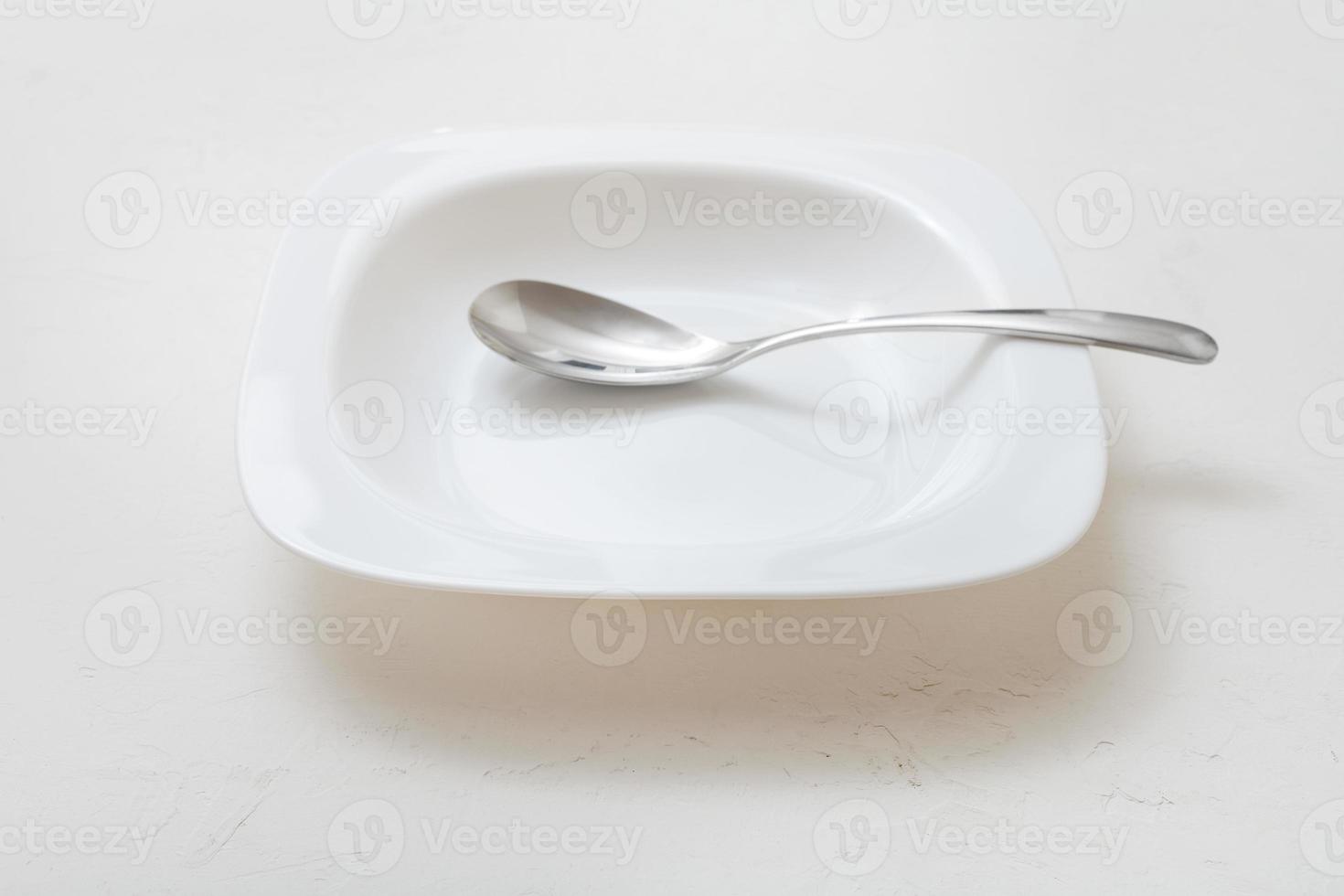 square white bowl with spoon on plaster photo