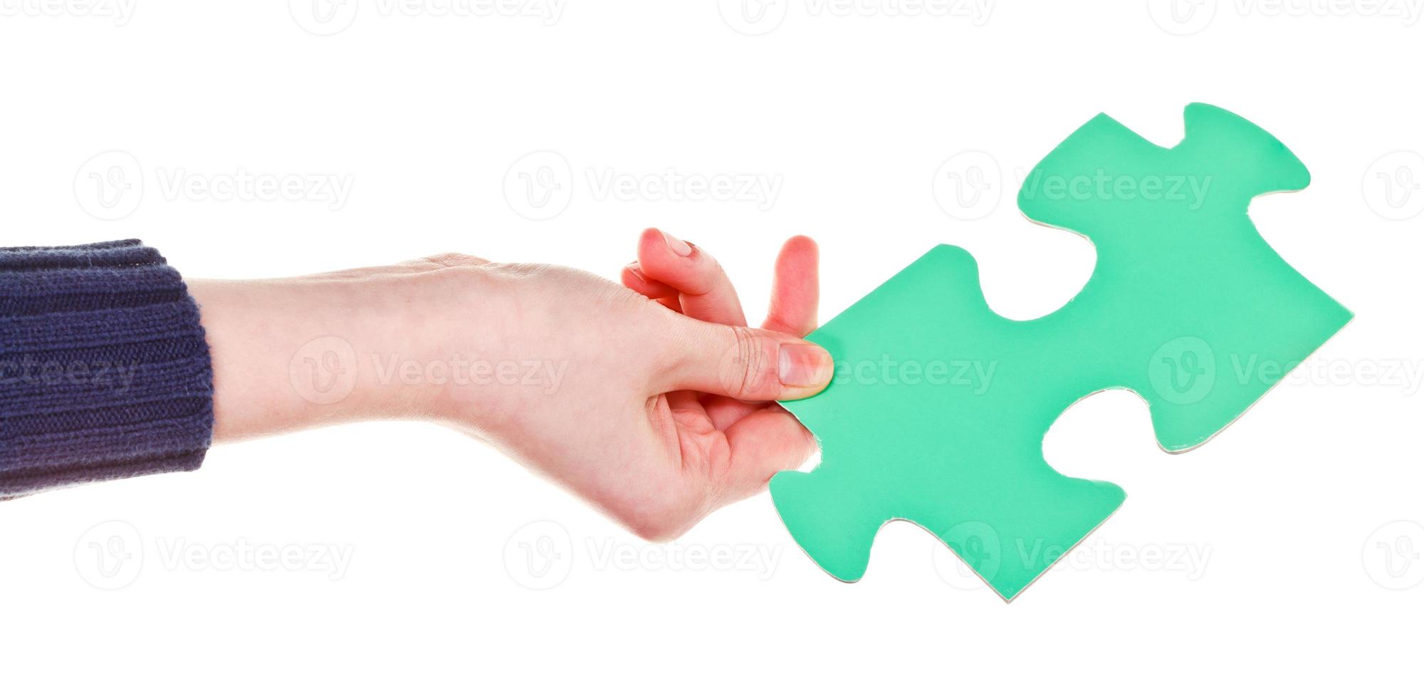 female hand holding big green paper puzzle piece photo