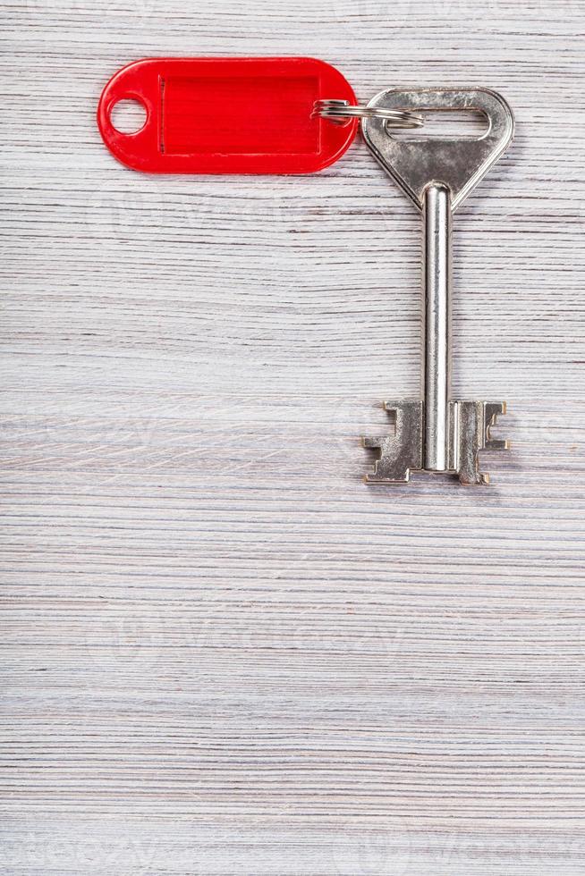 llave grande con llavero rojo sobre superficie de madera foto