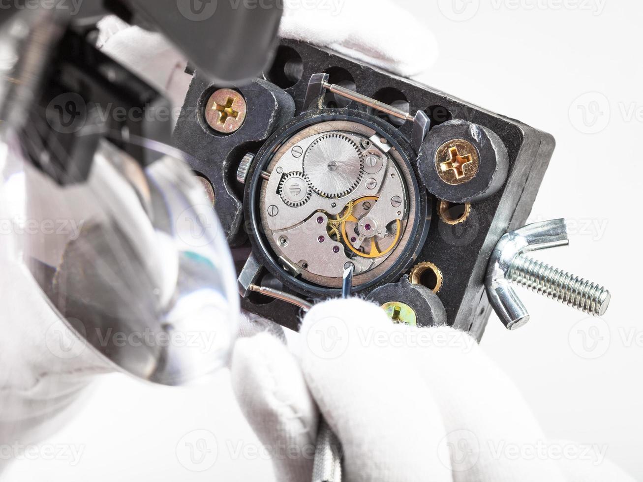 watchmaker in head-mounted magnifier repairs watch photo