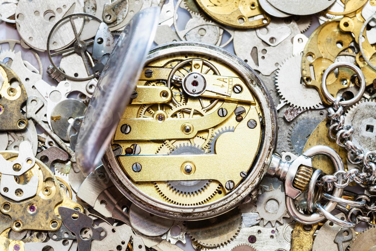 open vintage pocket watch on heap of spare parts photo