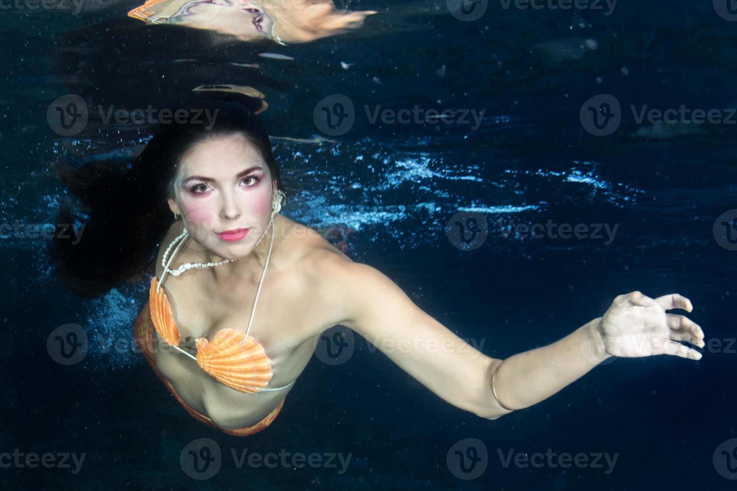 Mermaid swimming underwater in the deep blue sea photo