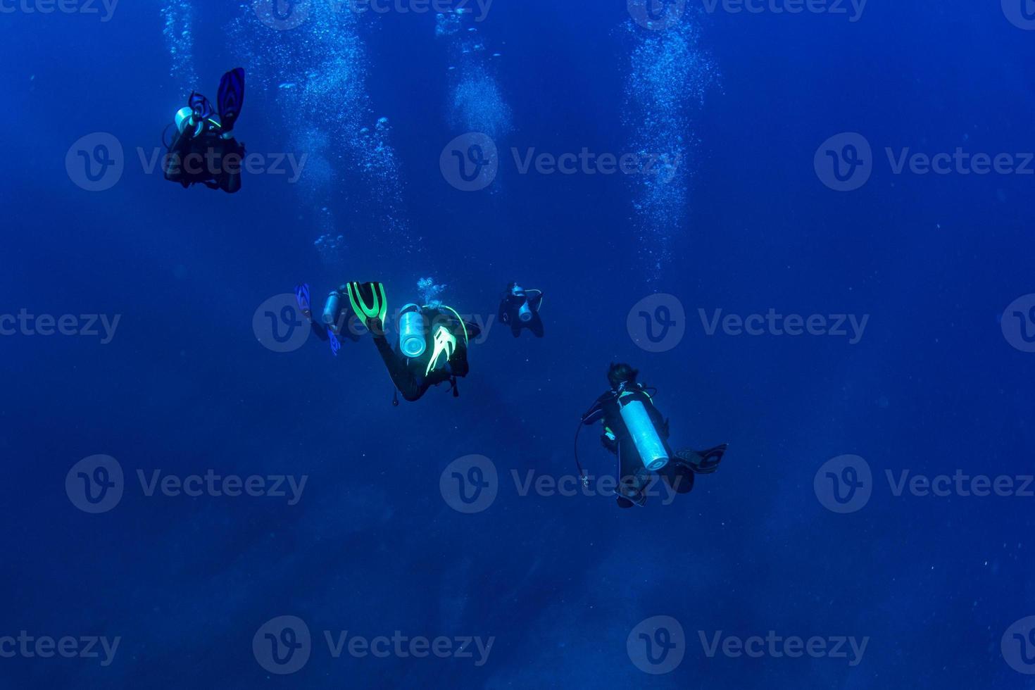 Scuba diver underwater in the deep blye ocean abyss photo