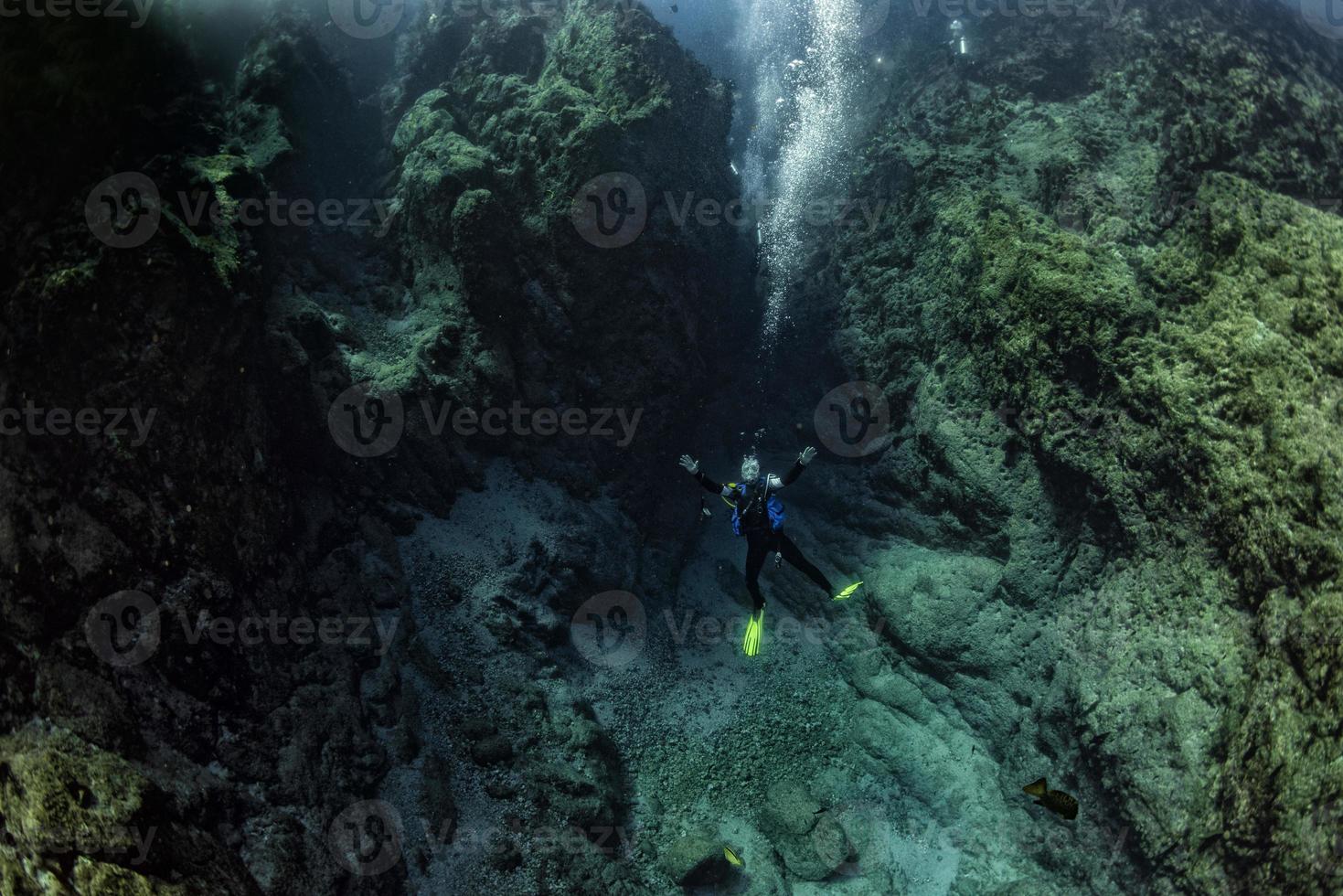 Scuba diver underwater in the deep blye ocean abyss photo