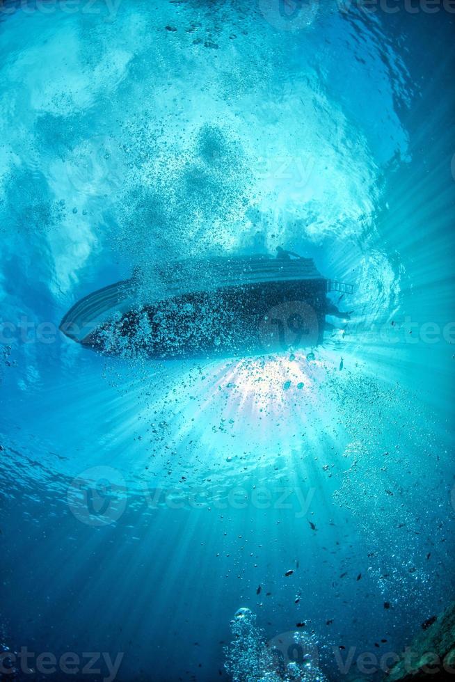 diving boat ship from underwater blue ocean with sun rays photo