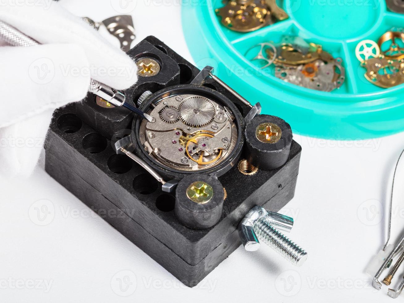 repairing old wristwatch close up on white table photo