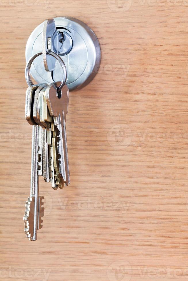 bunch of house keys in lock of wood door photo