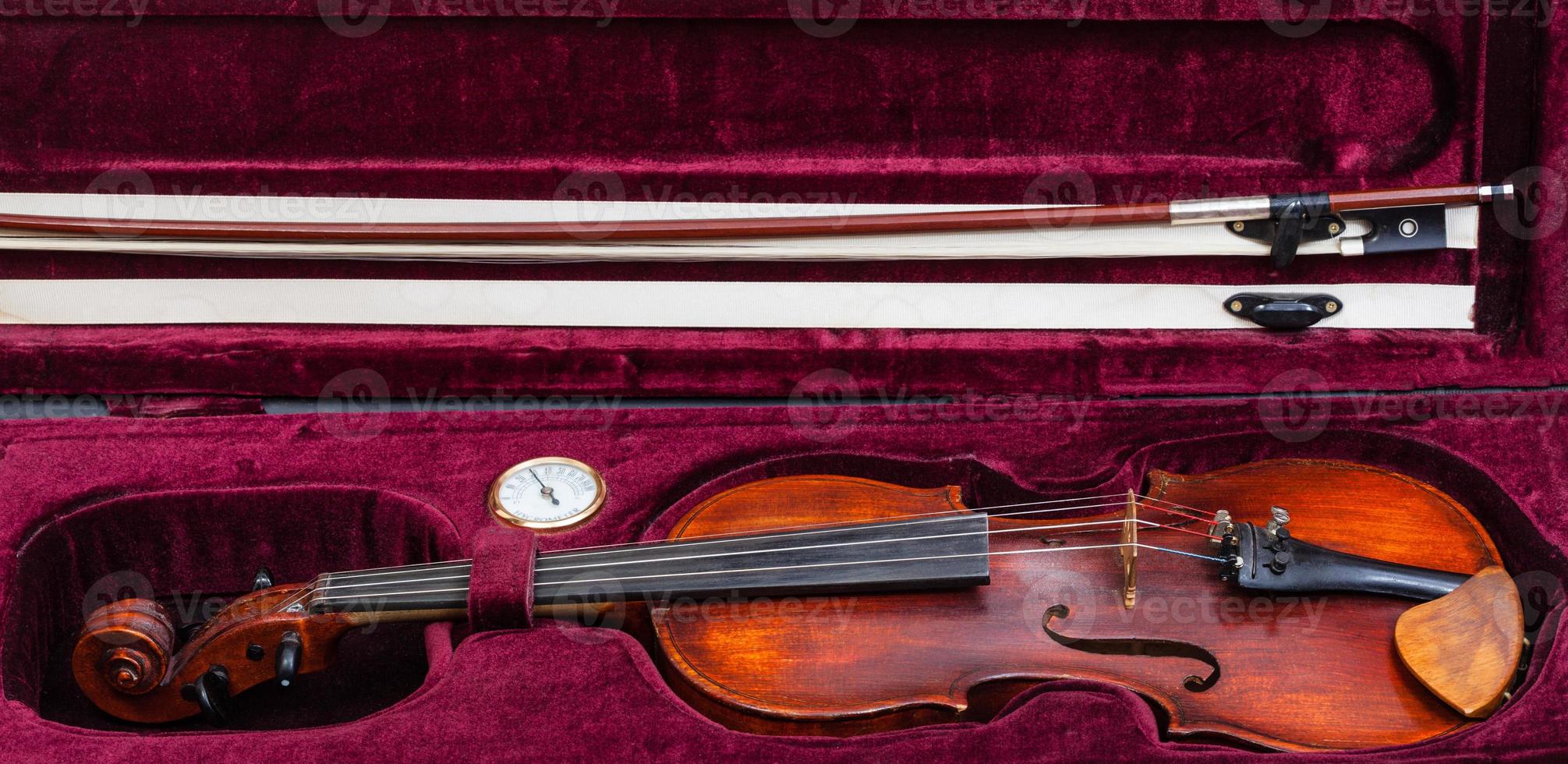viejo violín con arco en estuche de terciopelo rojo foto