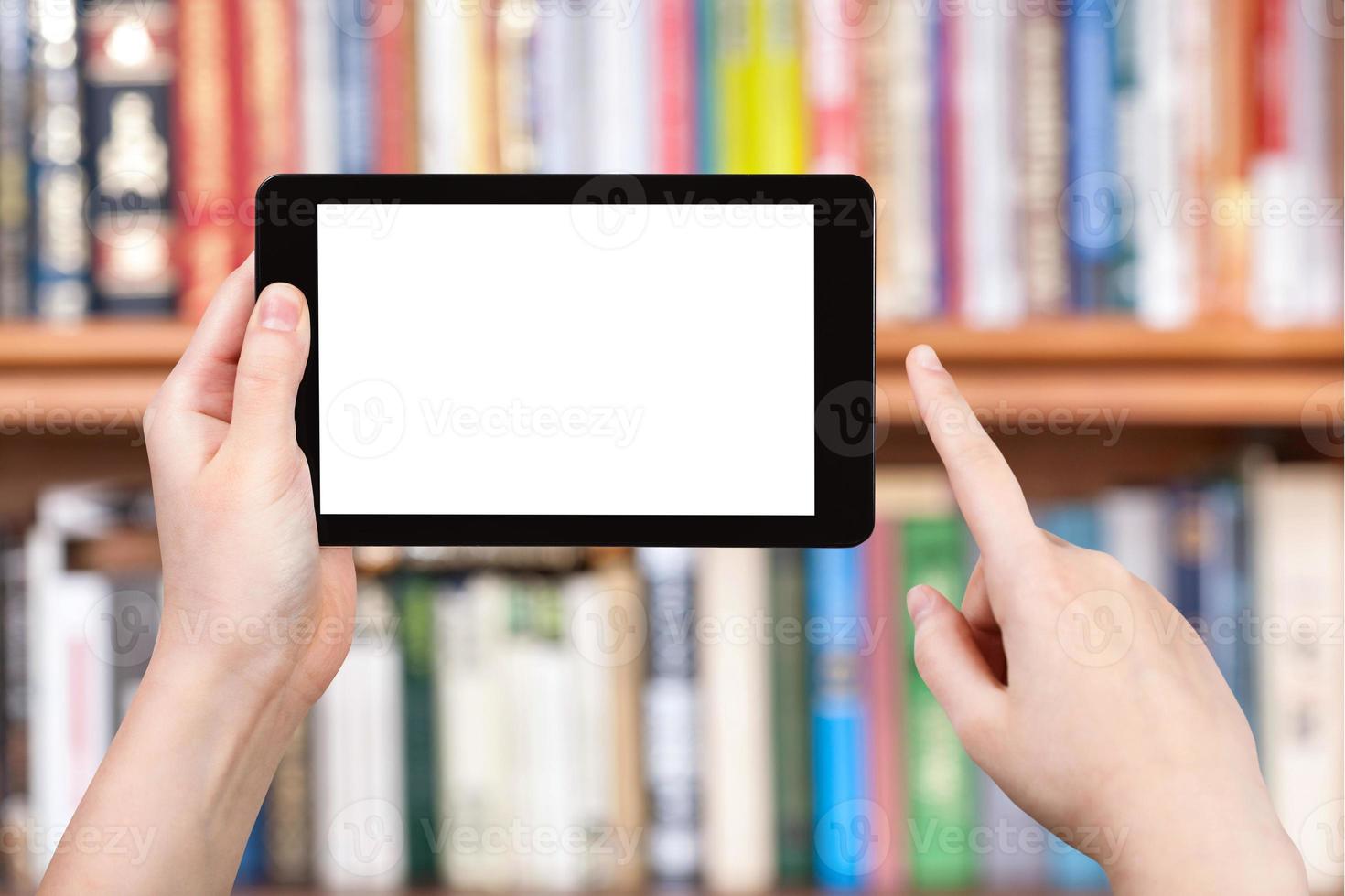 la mano sostiene la tableta y los estantes para libros foto