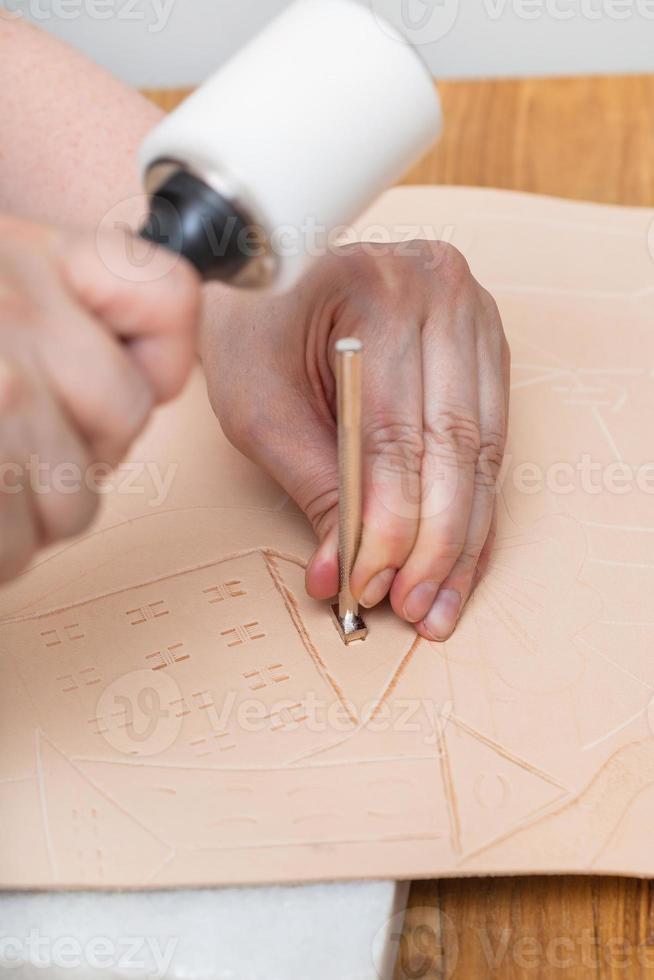 craftsman puts image on leather by stamping tool photo