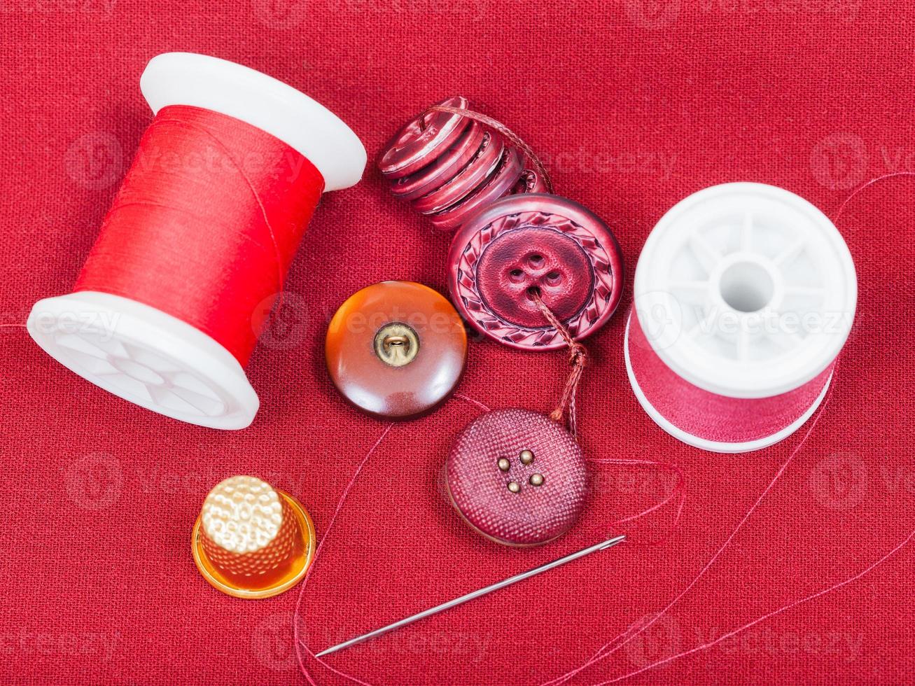 sewing thread, buttons, thimble on red tissue photo