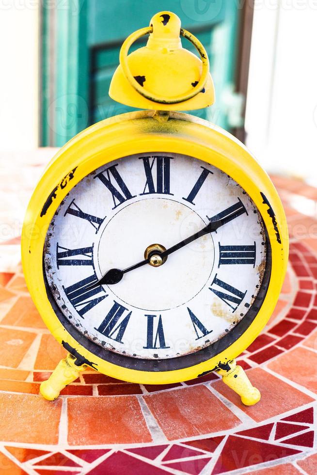 old yellow mechanical alarm clock on stone table photo