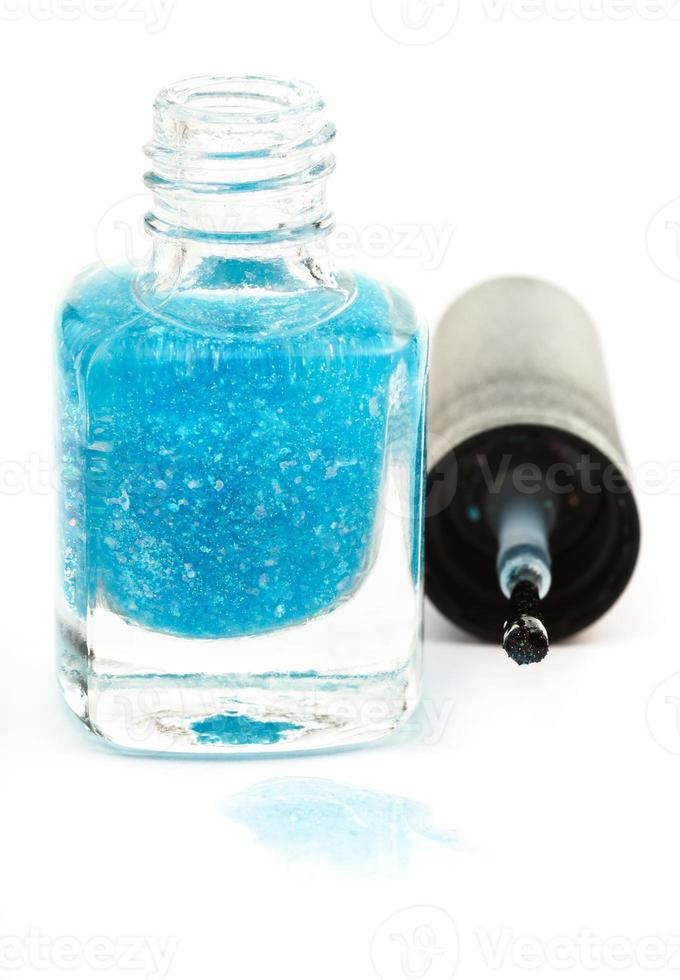 bottle with spilled turquoise nail polish on white photo