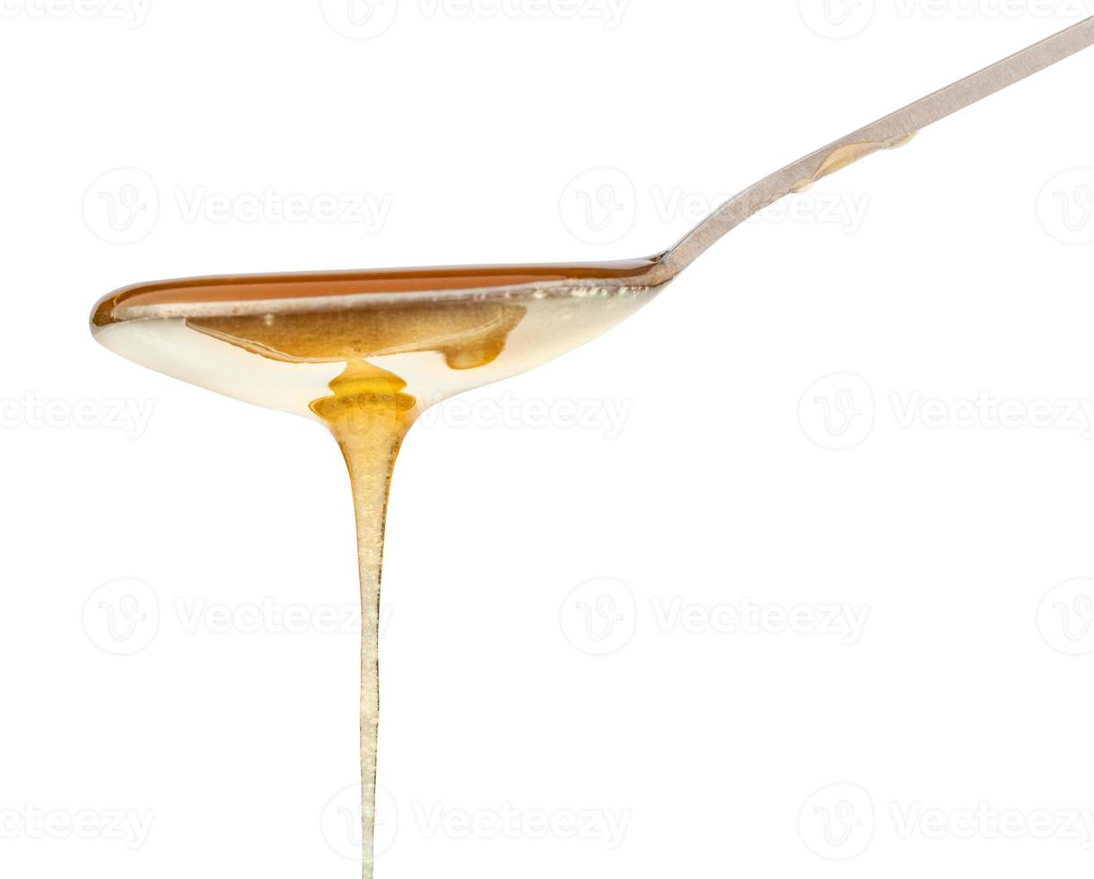 clear honey flowing down from teaspoon close up photo