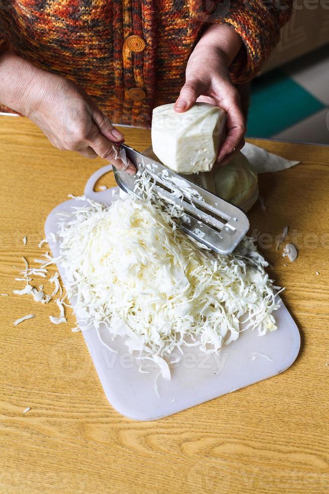 https://static.vecteezy.com/system/resources/previews/012/254/218/non_2x/woman-shredding-cabbage-by-manual-slaw-cutter-photo.jpg