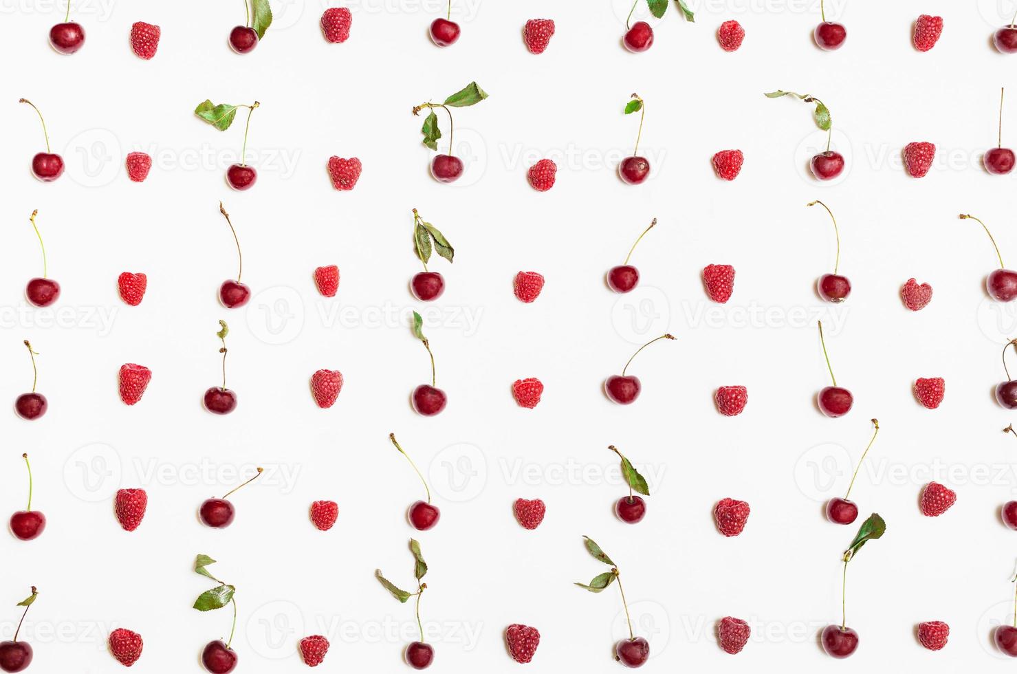 many raspberries and cherries arranged on white photo