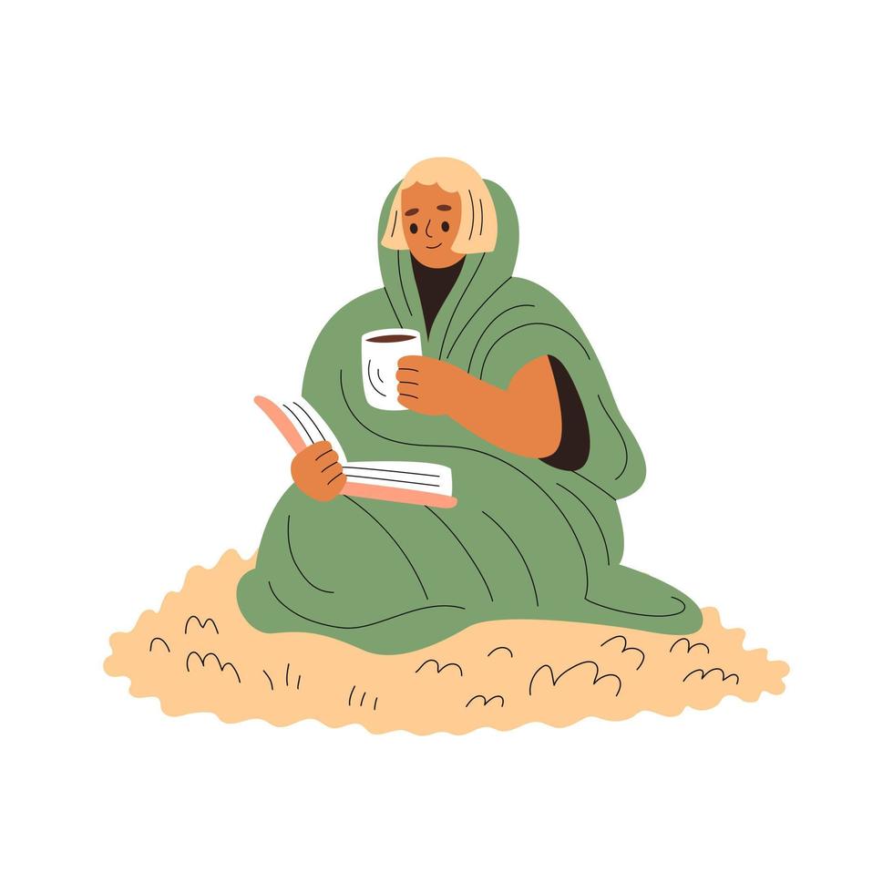 Smiling girl wrapped in a blanket sits on a wool carpet and reads, holding a cup of warm drink vector