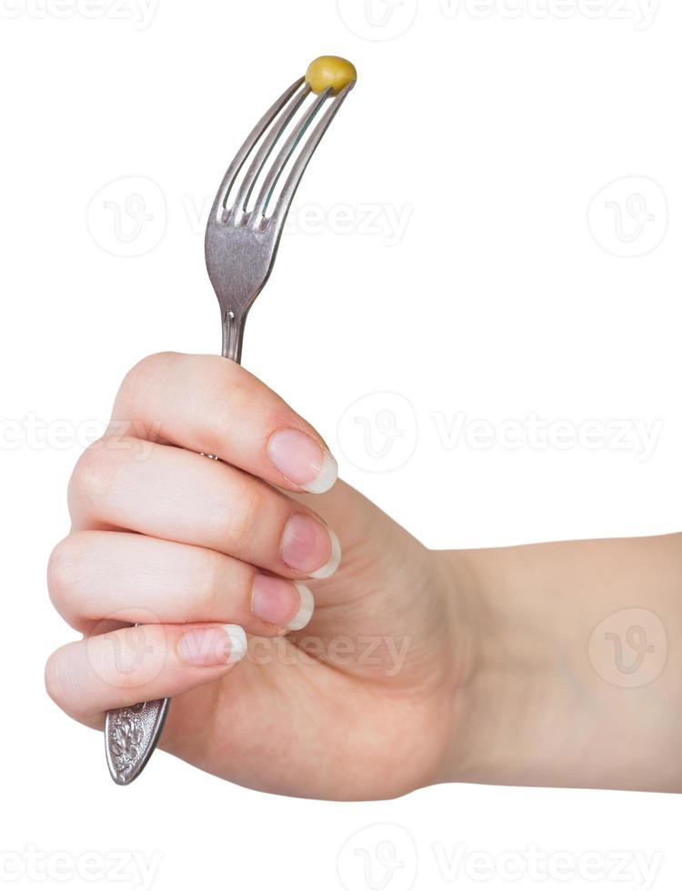 hand holding dinning fork with impaled green pea photo