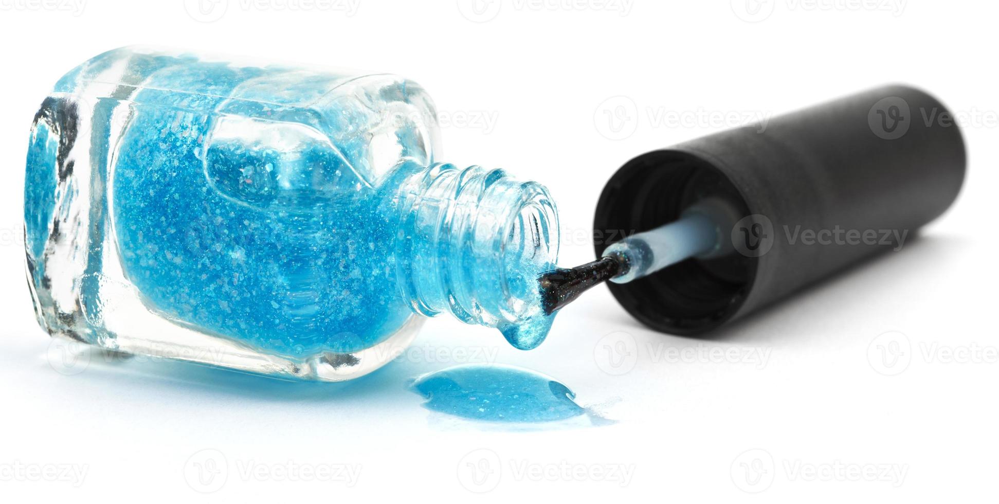 botella y charco de esmalte de uñas azul foto