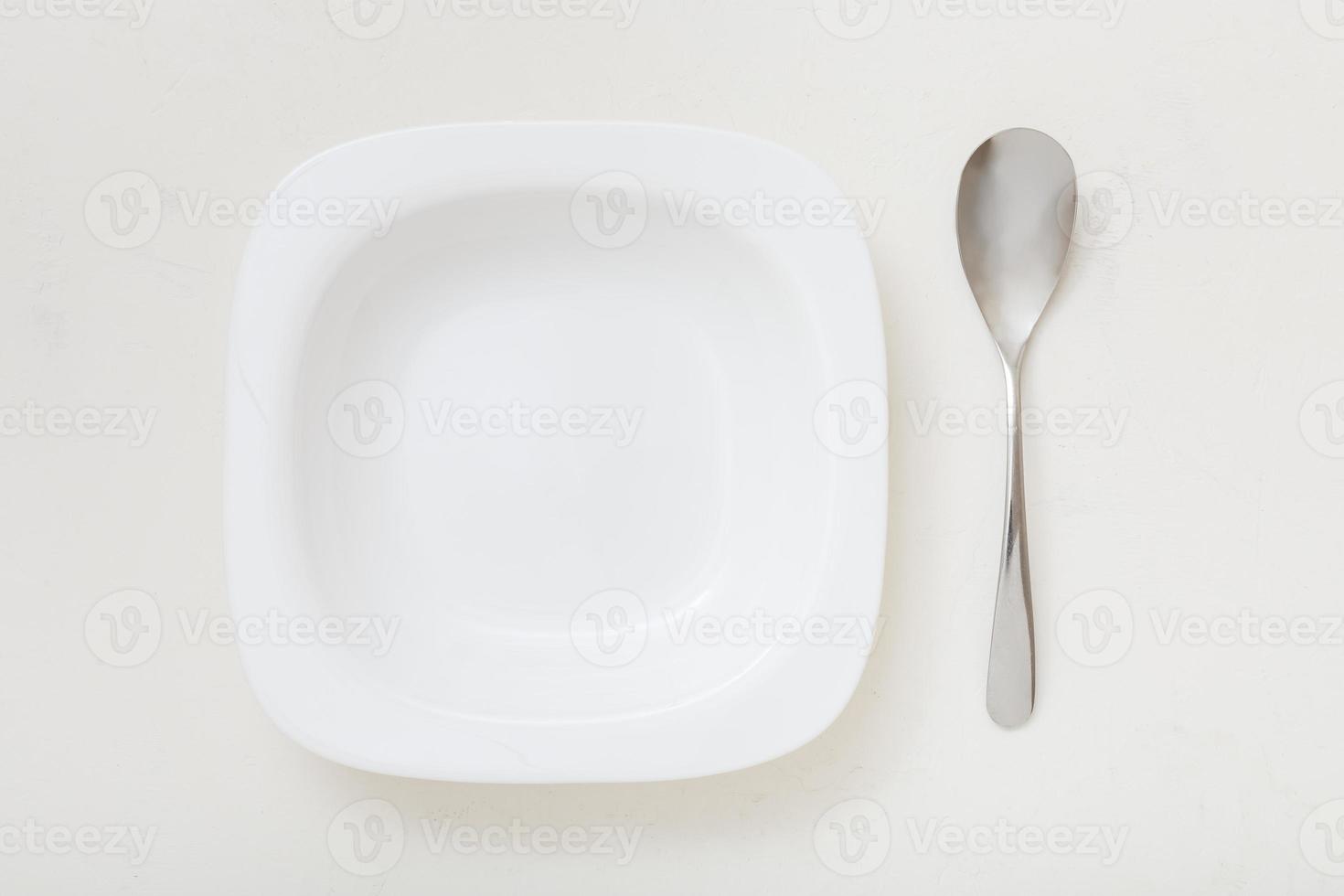 top view of square white bowl and spoon on plaster photo