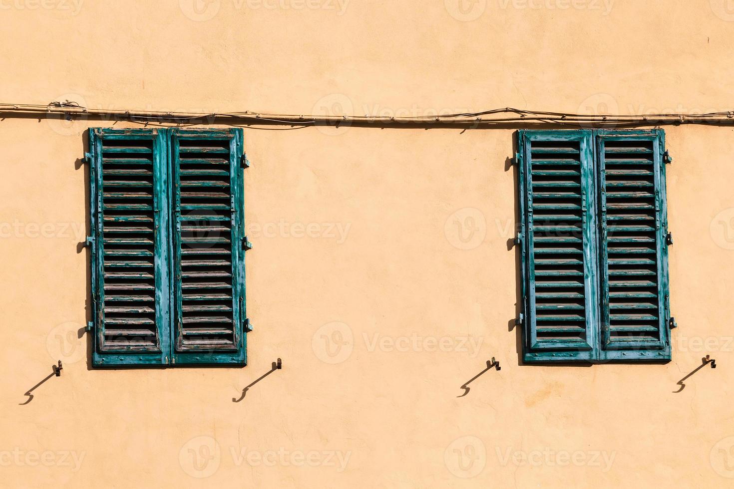 closed green windows on yellow wall of old house photo