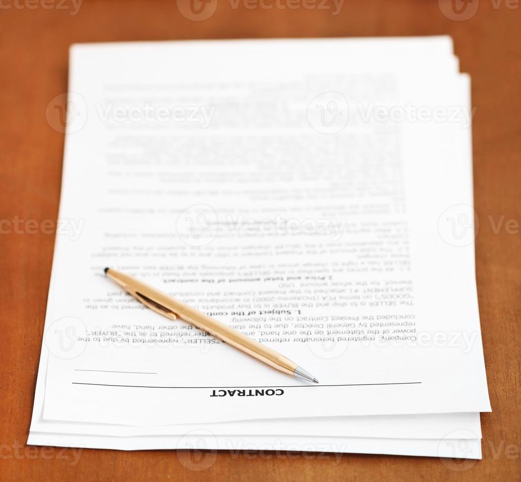 sheets of contract and golden pen on wooden table photo