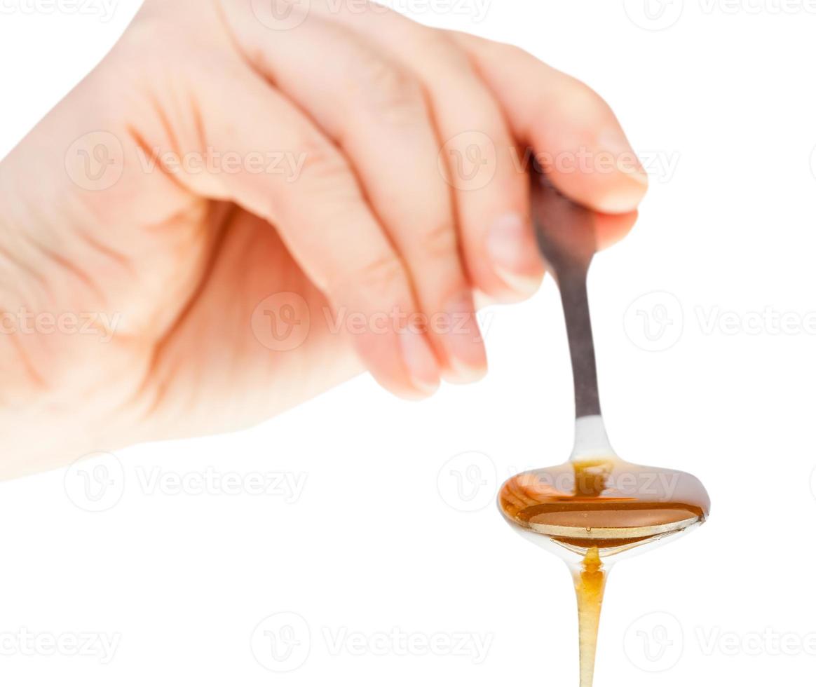 hand holds metal spoon with clear honey photo