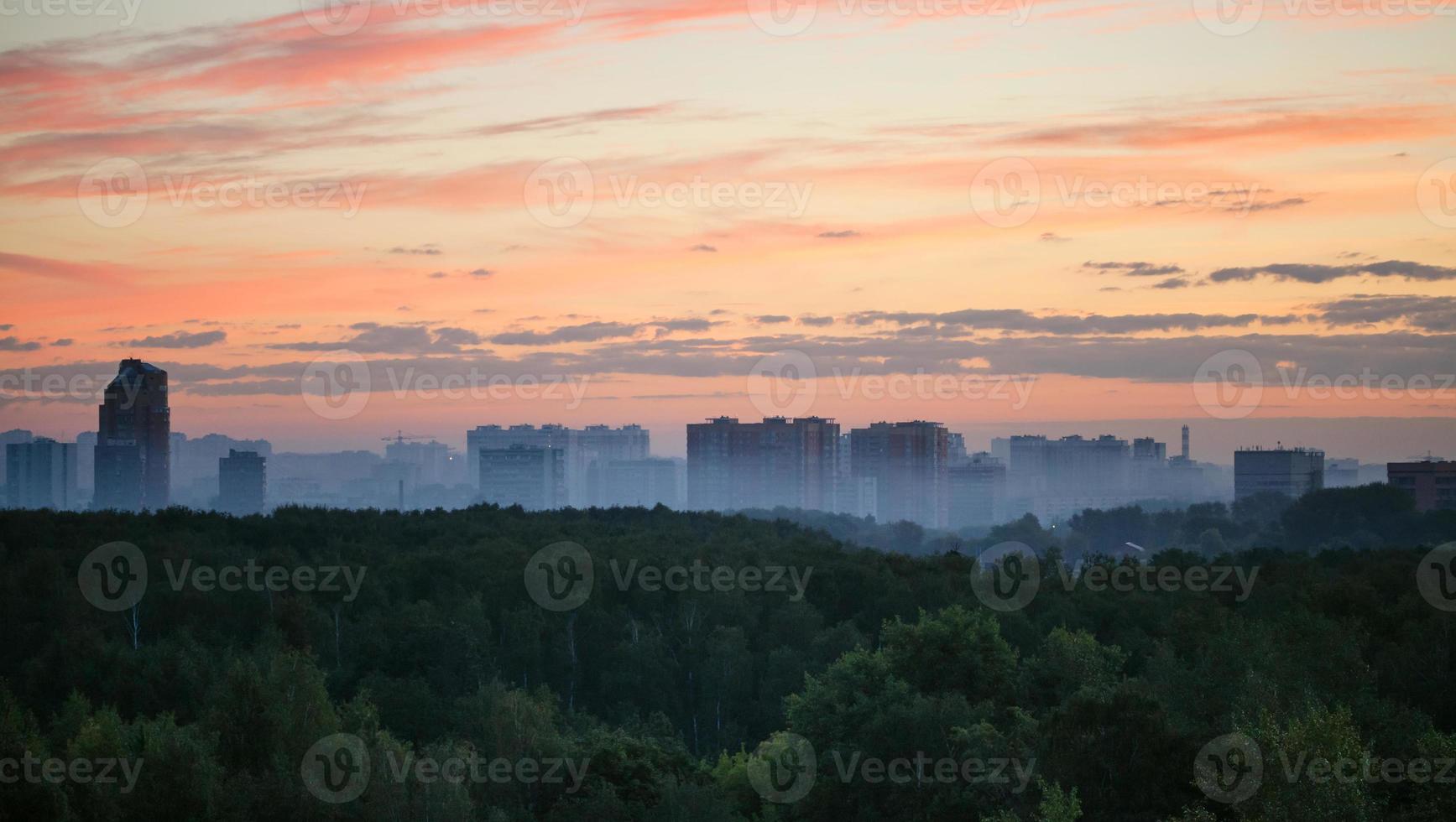 early sunrise and morning mist over woods and city photo