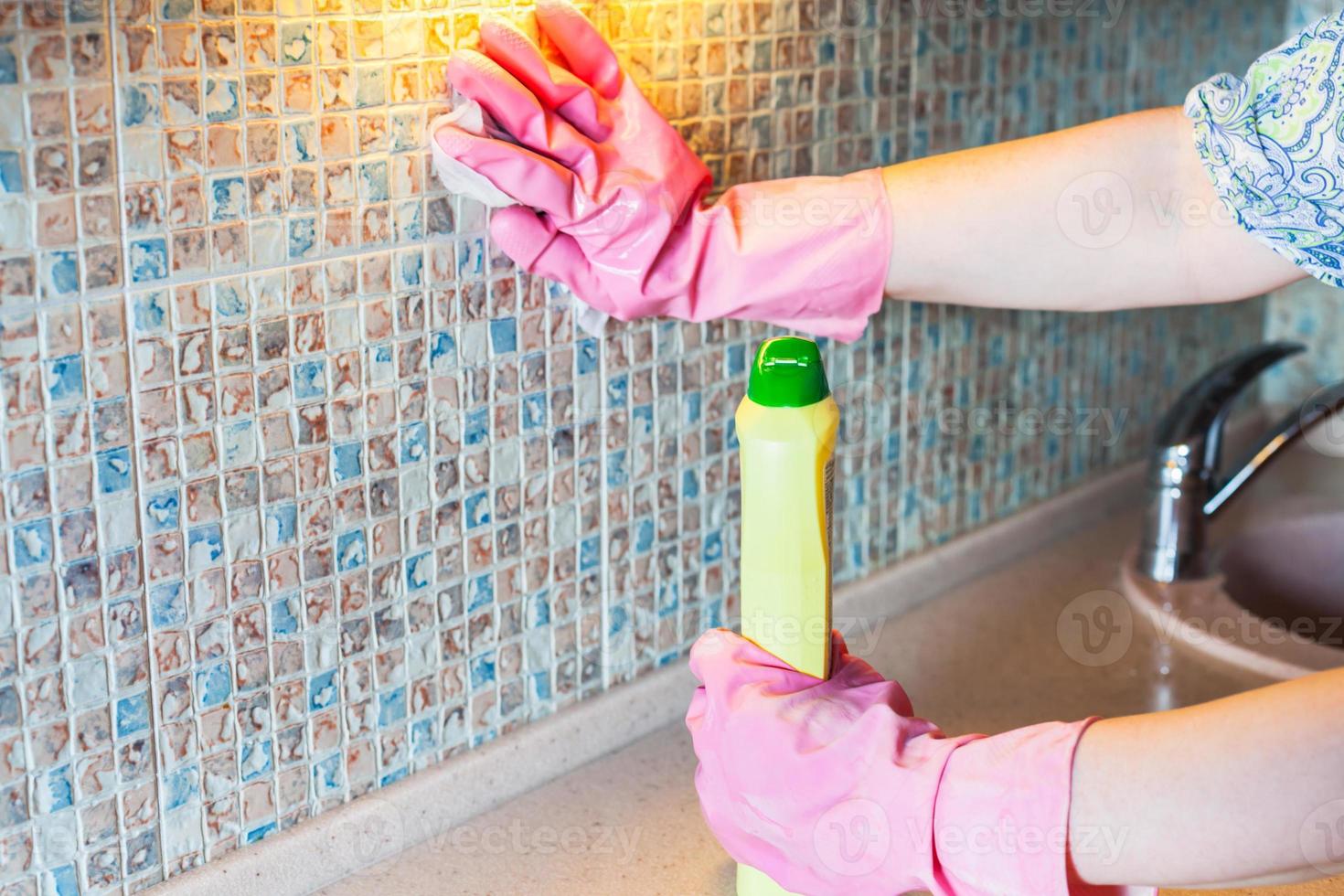 mujer lava la pared de la cocina con detergente foto