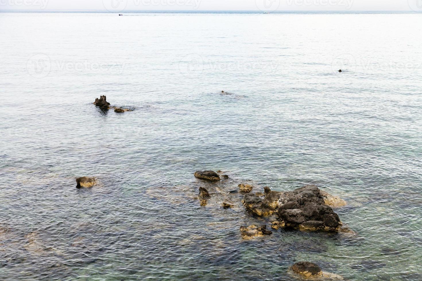 rocks in water near waterfront in Giardini Naxos photo