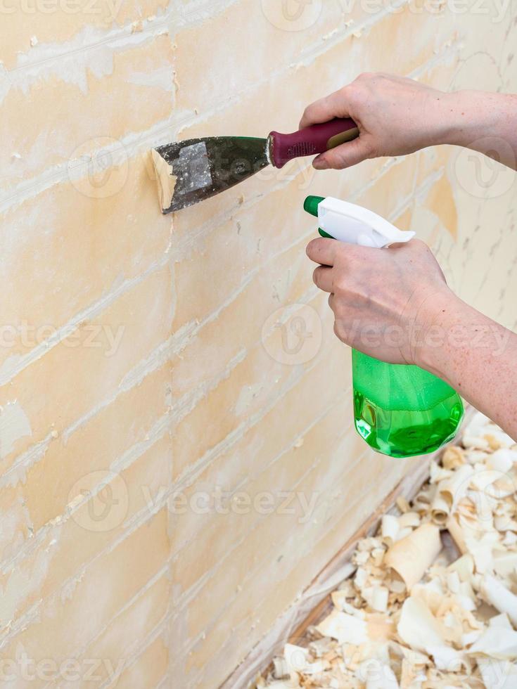 Removing of wet old wallpaper with metal spatula photo