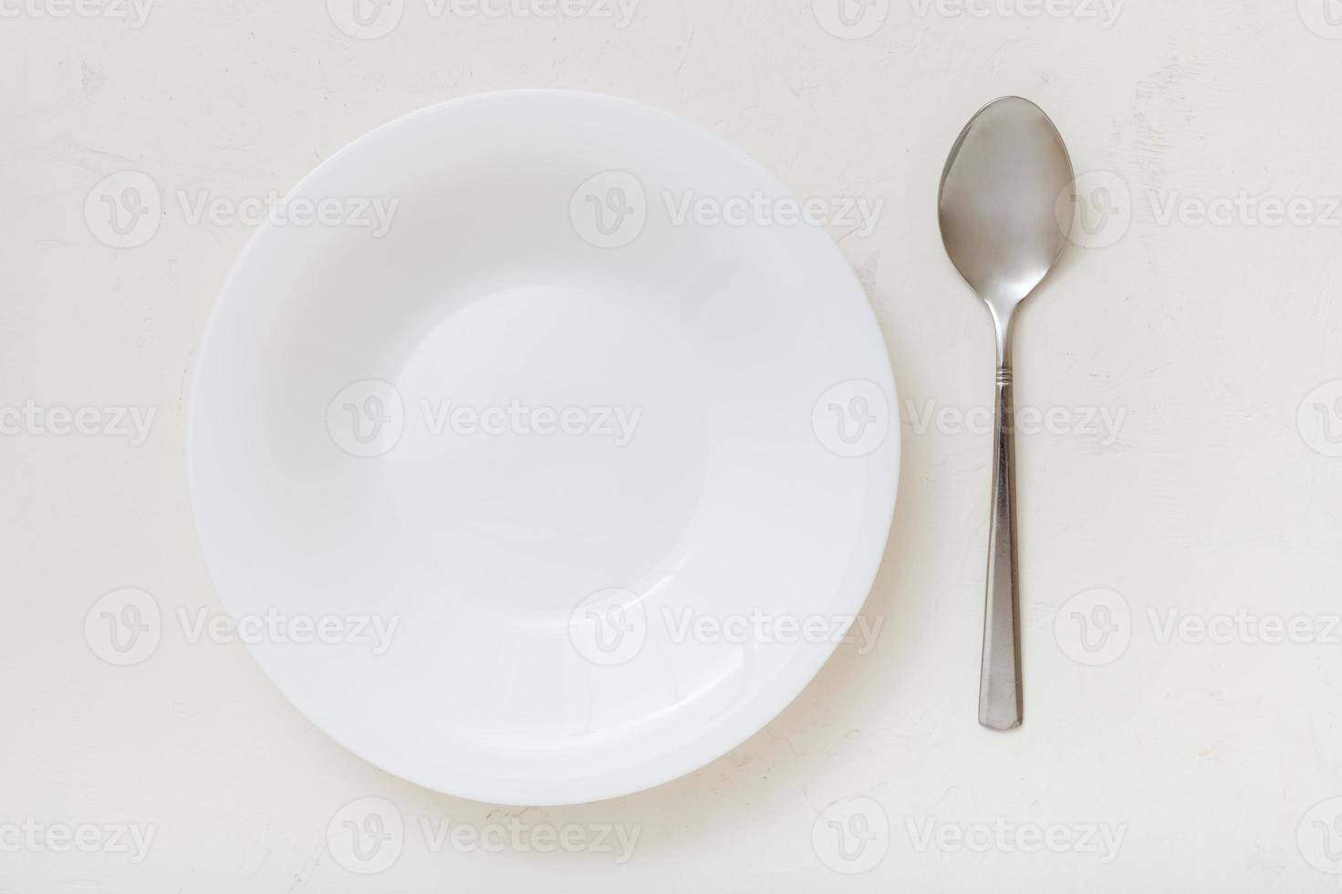 top view of white deep plate and spoon on plaster photo