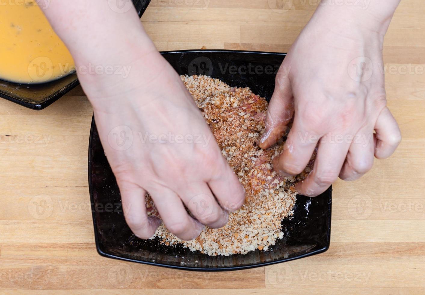 cook hands breading veal schnitzel in breadcrumbs photo