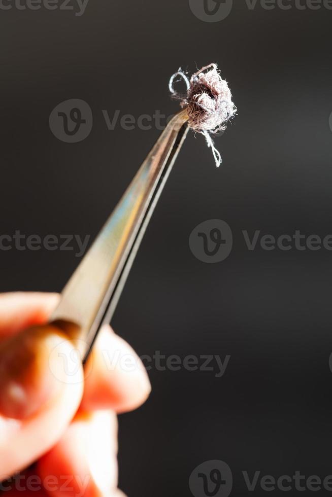 sample of textile fibers on top of tweezers photo