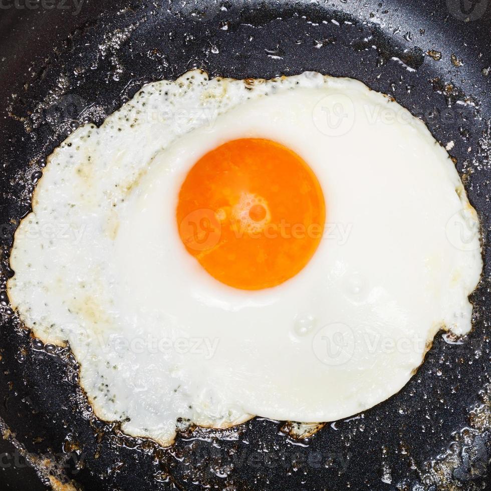 top view of one fried egg in black frypan photo