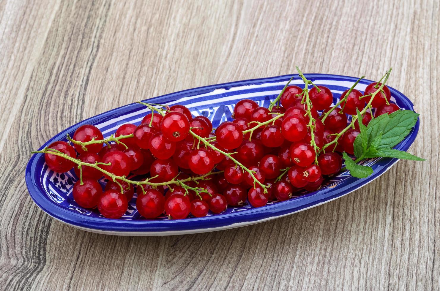 Red currants in a bowl on wooden background photo