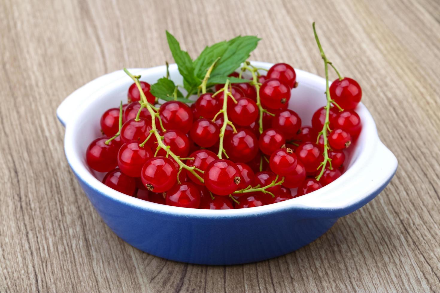 Red currants in a bowl on wooden background photo
