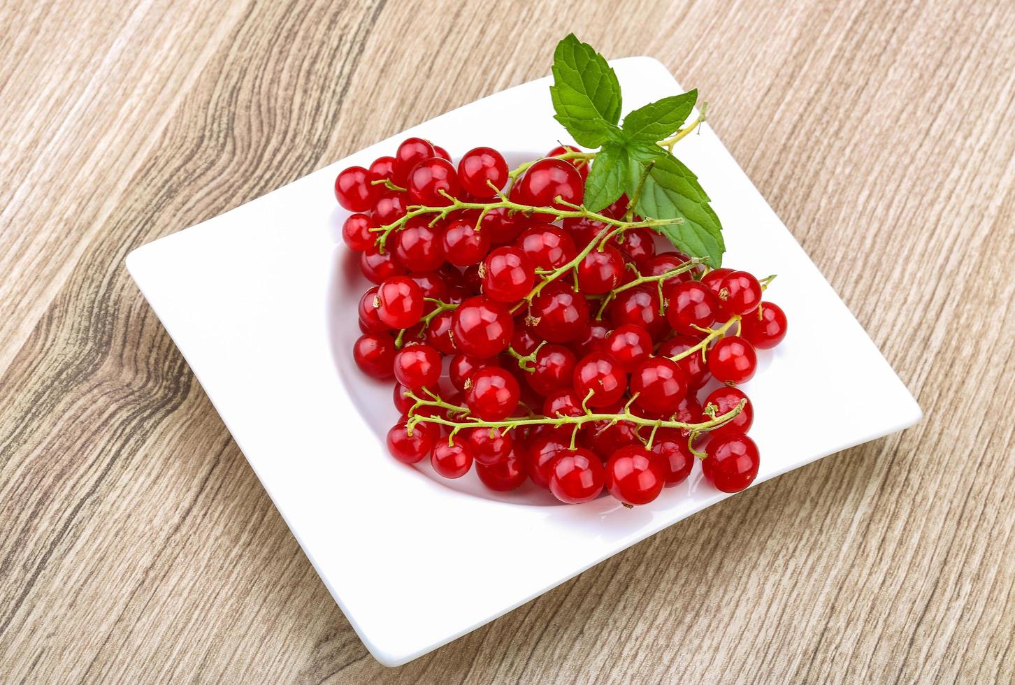 Red currants in a bowl on wooden background photo