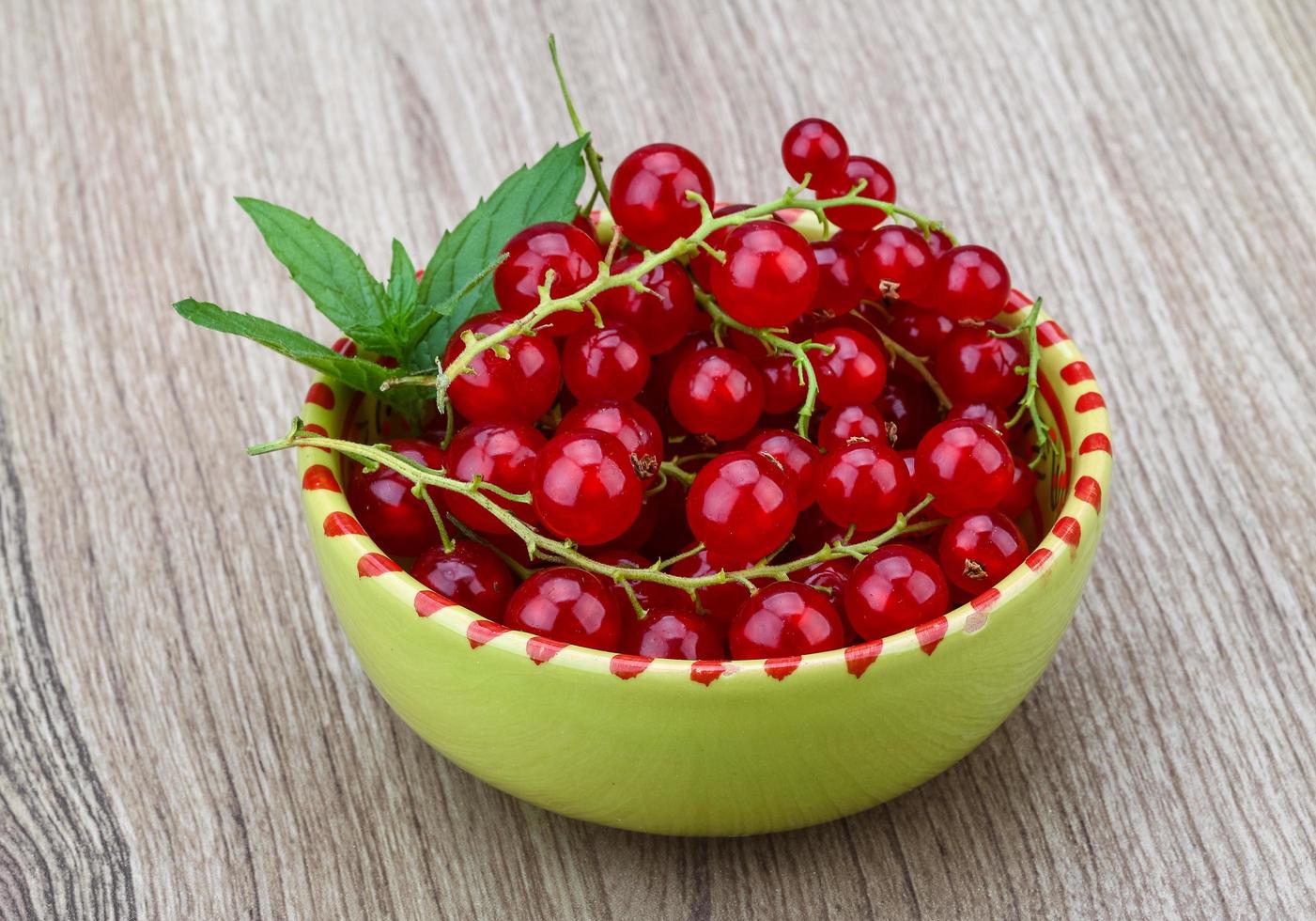 Red currant in a bowl on wooden background photo