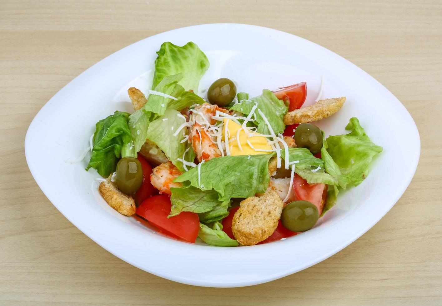 Caesar salad on the plate and wooden background photo