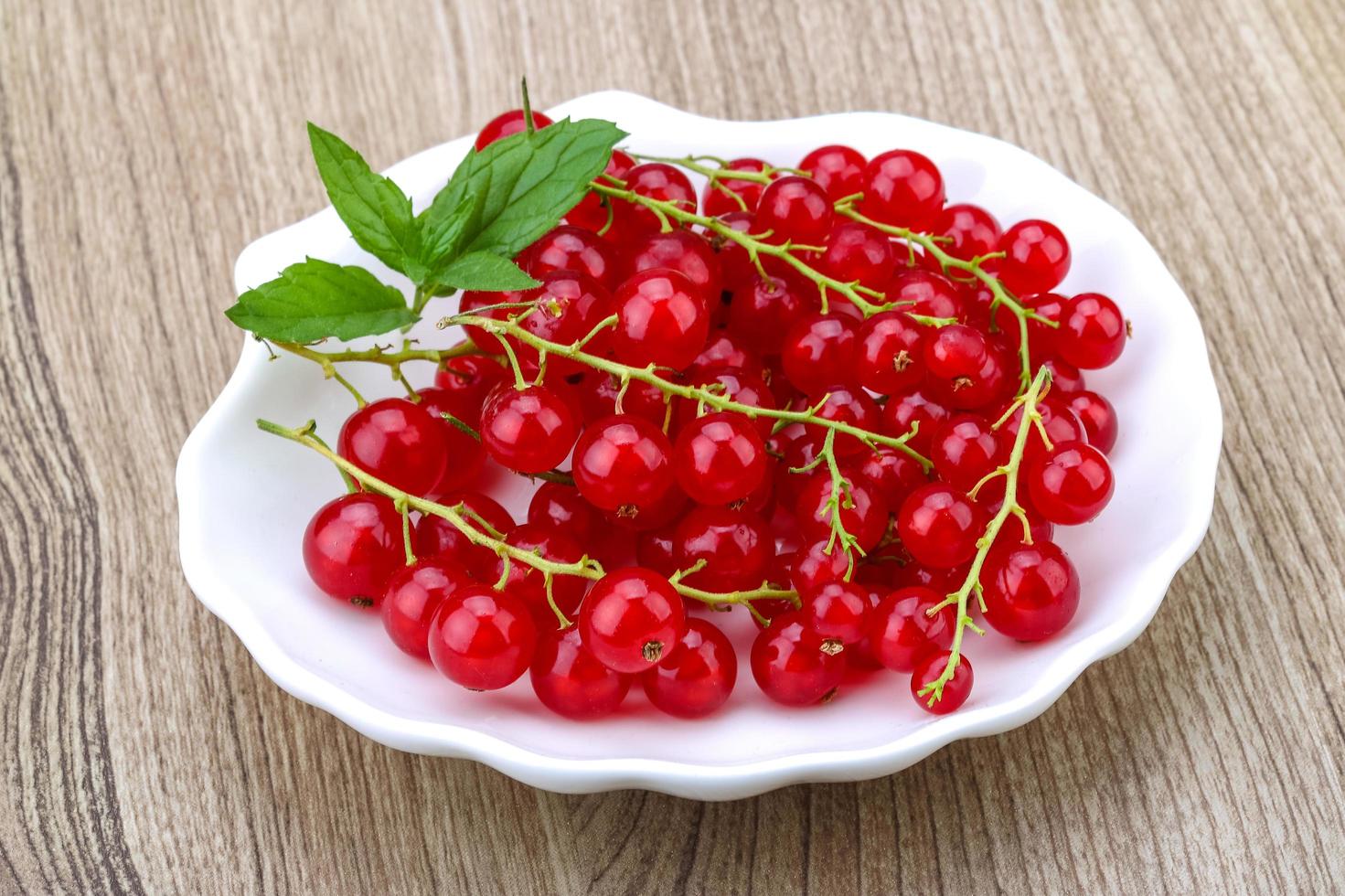 Red currants in a bowl on wooden background photo