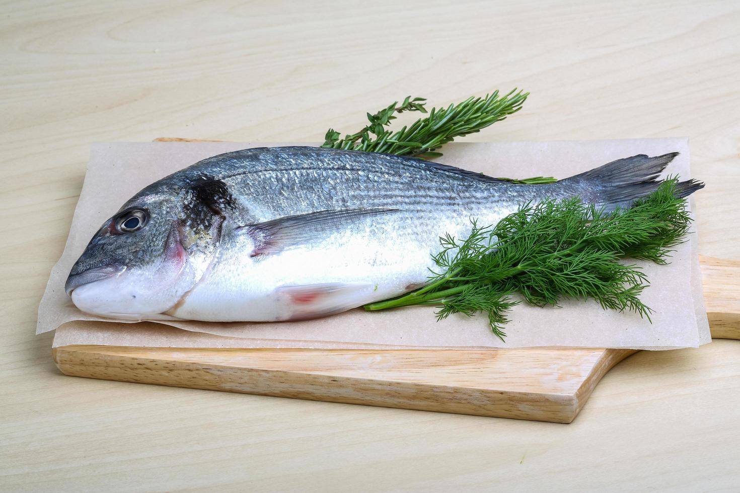 Raw dorado on wooden board and wooden background photo