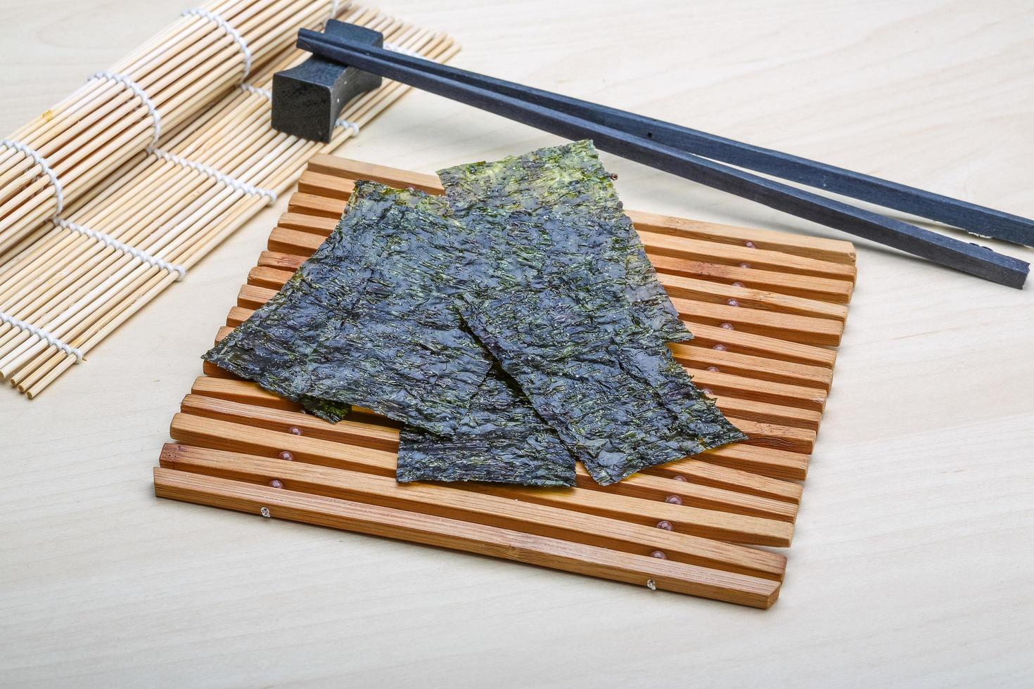 Nori sheets on wooden board and wooden background photo