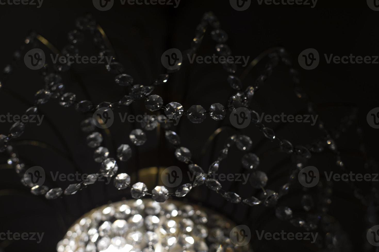 Crystal chandelier made of glass. Chandelier in interior. Light in dark. Reflection of light in glass. photo