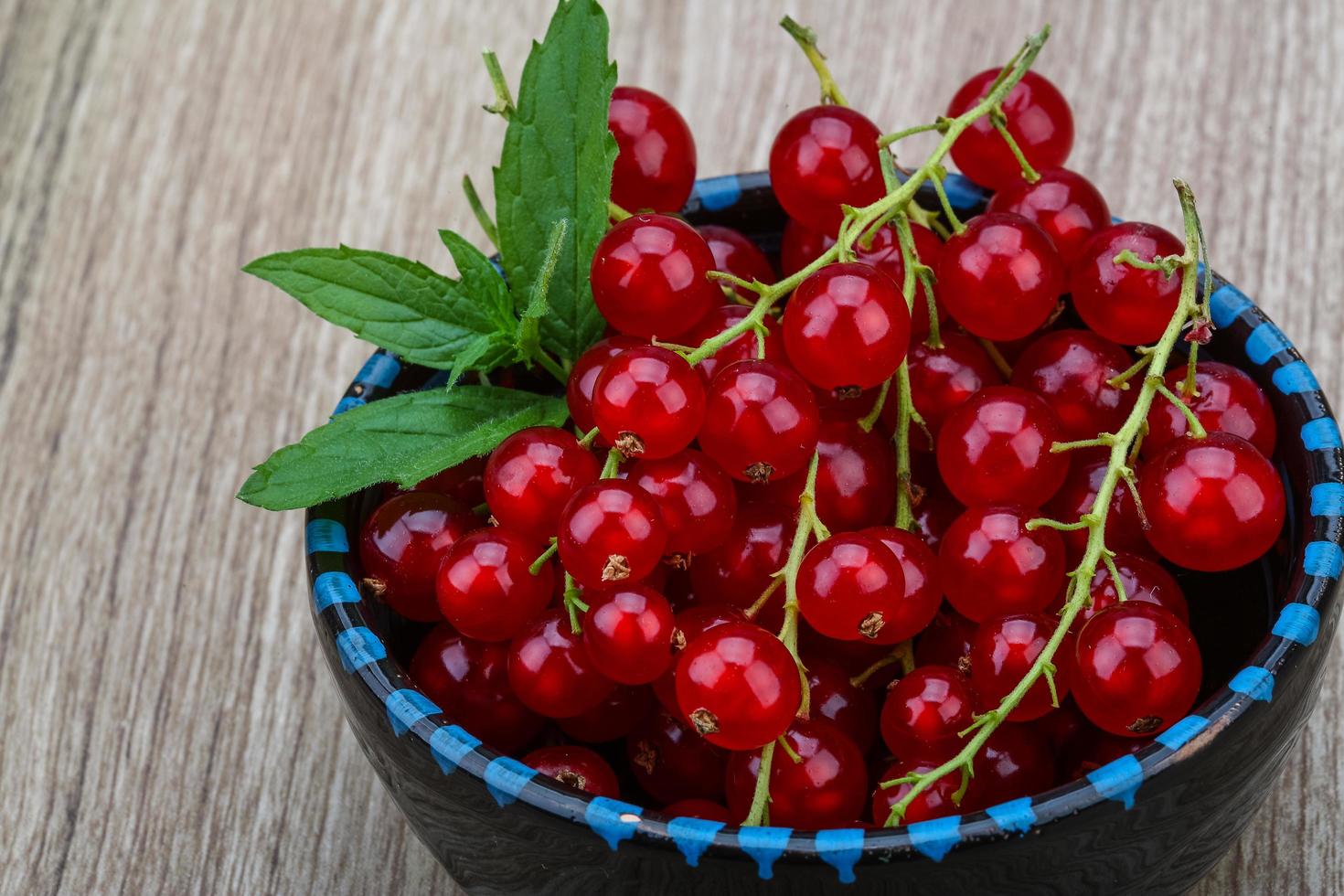 Red currants in a bowl on wooden background photo