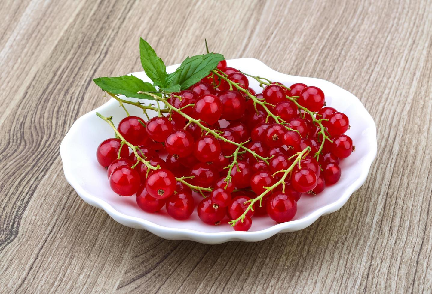 Red currants in a bowl on wooden background photo