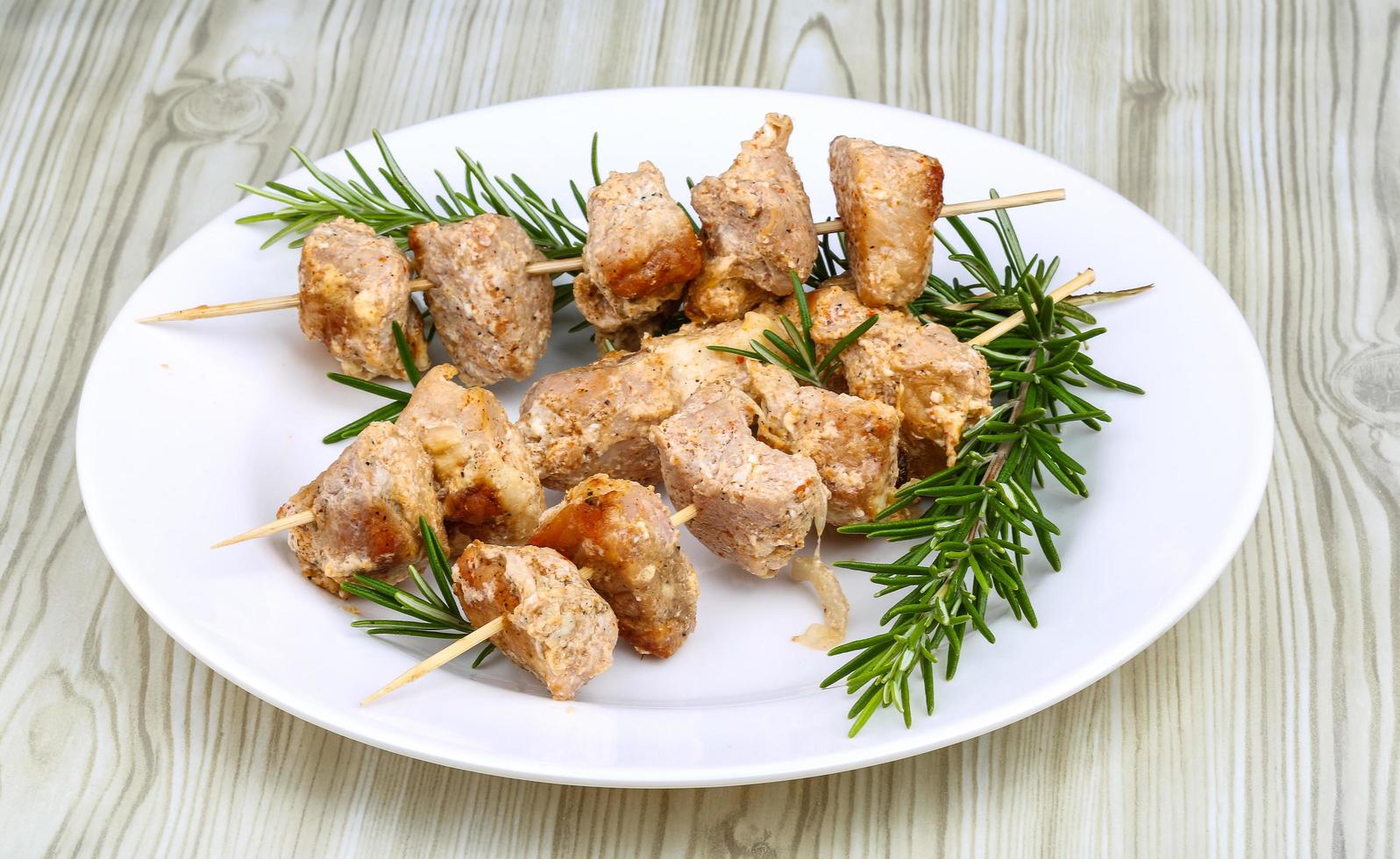 Chicken skewers on the plate and wooden background photo