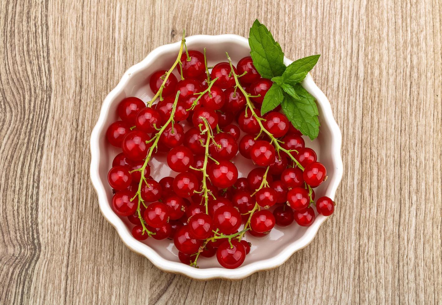 Red currants in a bowl on wooden background photo
