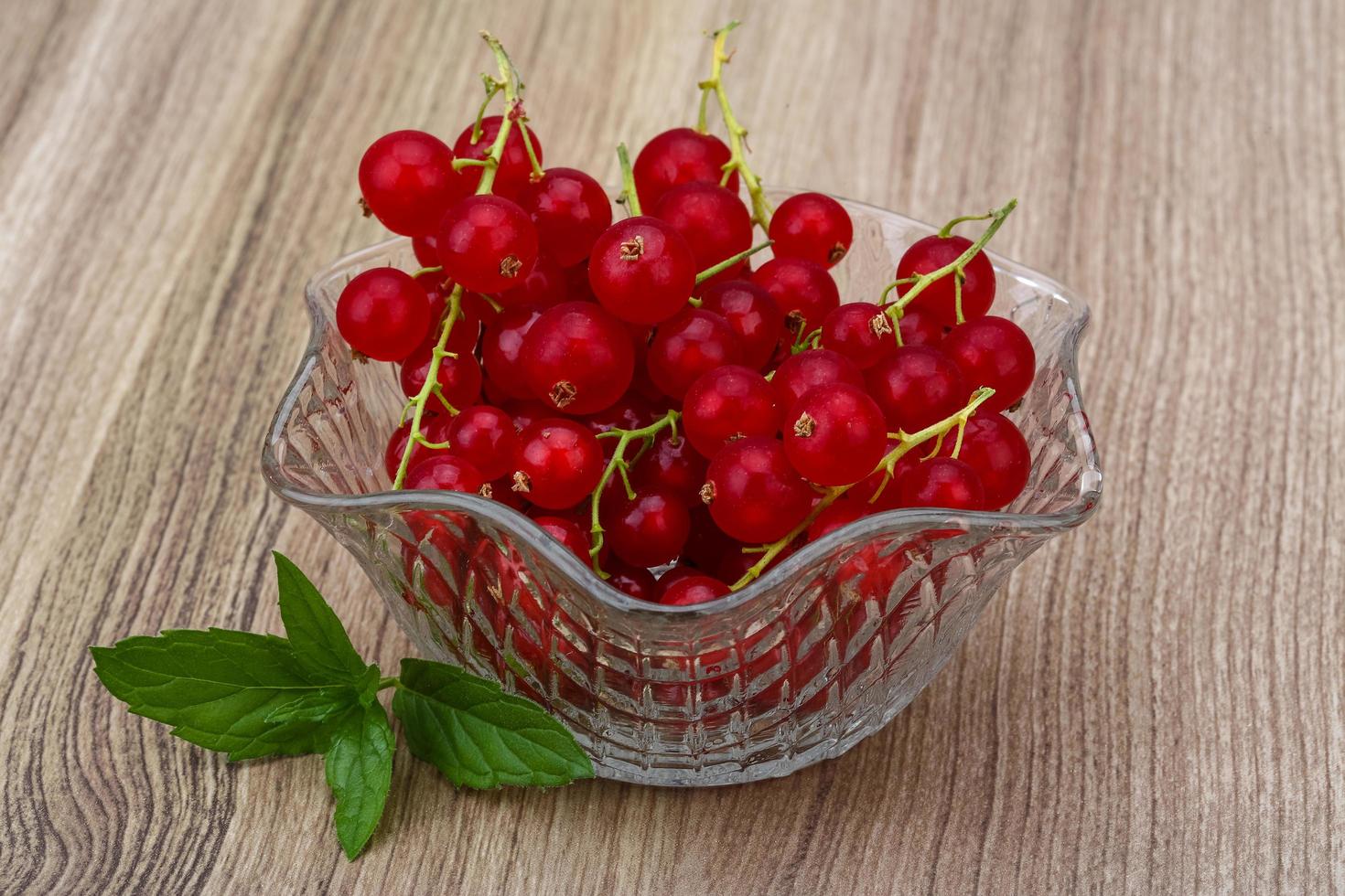 Red currant in a bowl on wooden background photo