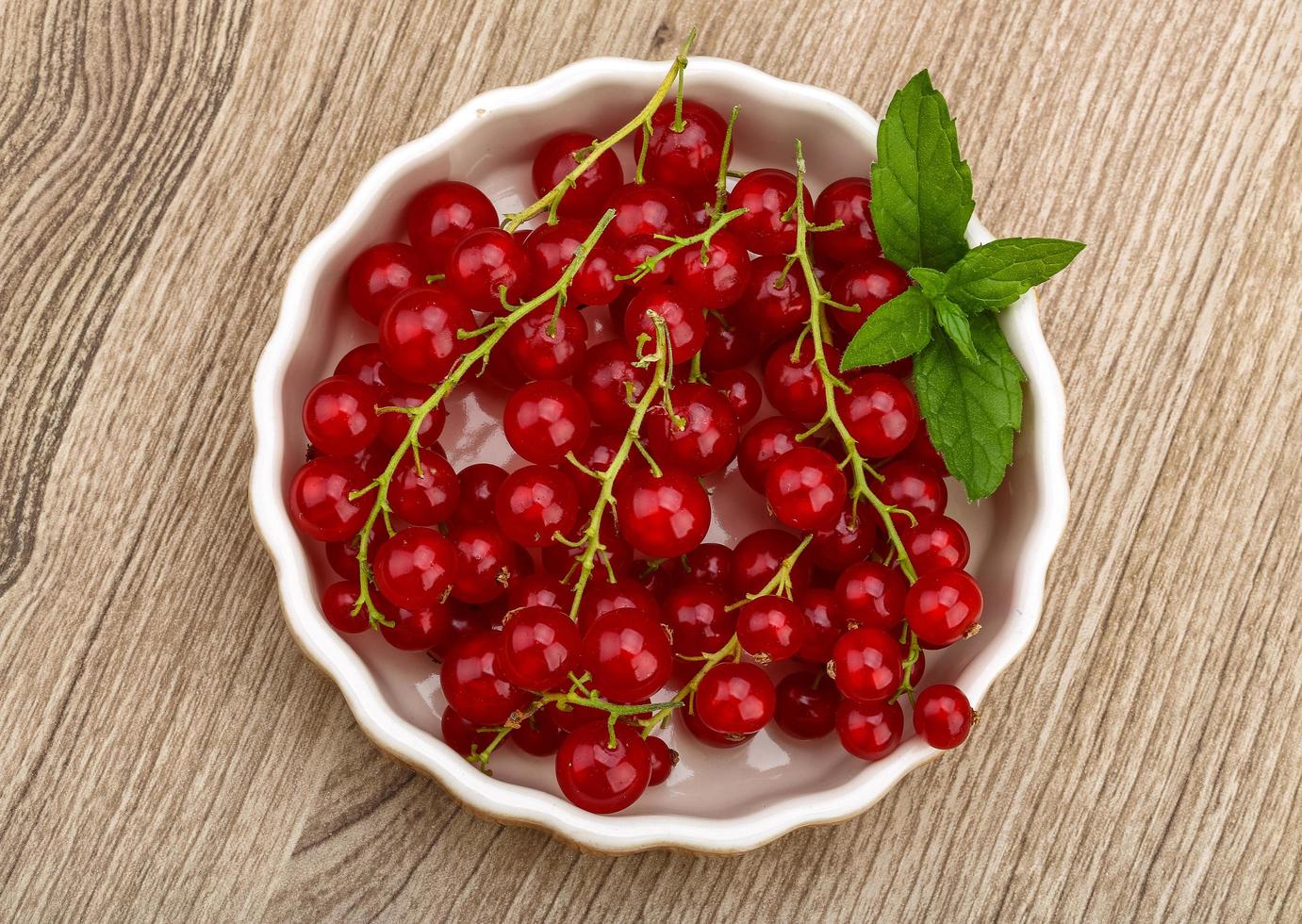 Red currants in a bowl on wooden background photo